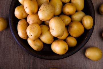 Potatoes in a rustic plate. Raw new potato. Fresh natural vegetables. Organic bio food on wooden table.