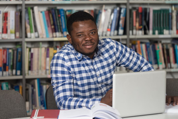 Happy African Male Student With Laptop In Library