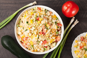 Tabbouleh salad with couscous, tomatoes, onion, zucchini and bell peppers topped with basil leaf horizontal shot