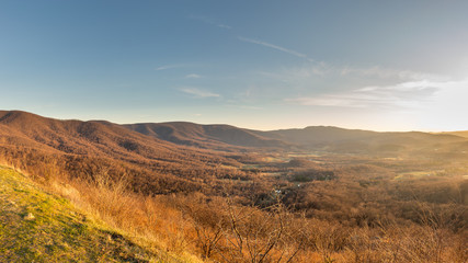 Naklejka na ściany i meble The Shenandoah valley shines a golden glow just before sunset with the mountains of Shenandoah National Park rising above