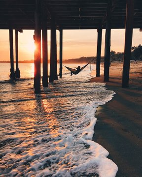 Teenage boy drinking water, in a hammock under the pier, Aptos, California, America, USA