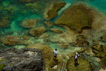 Two men stand on edge of crystal blue bay