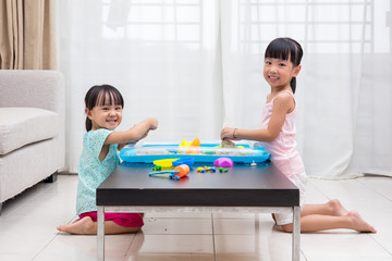 Happy Asian Chinese little girls playing kinetic sand at home