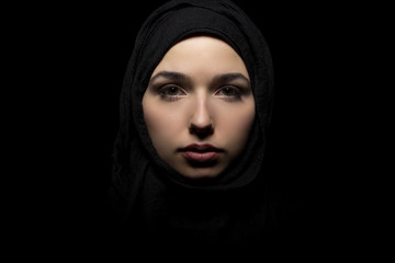 Female wearing a black hijab as a conservative fashion choice to represent feminist freedom of expression and political statement.  The headscarf is associated with muslims and middle eastern culture.