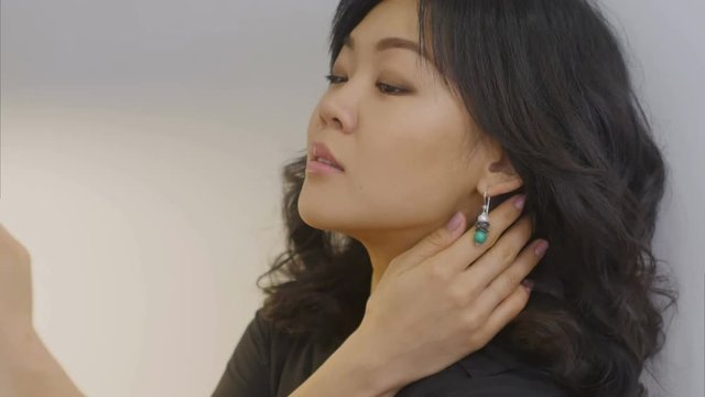 Young asian woman takes selfie in new designed earrings using smartphone