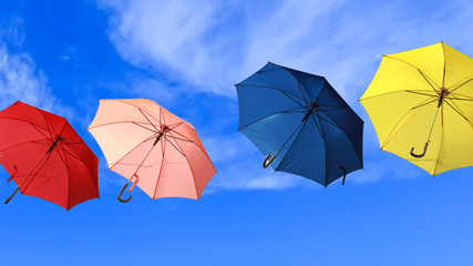Flying colorful umbrellas blue sky background