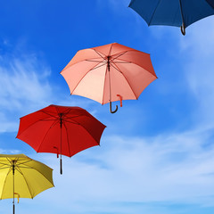 Flying colorful umbrellas blue sky background