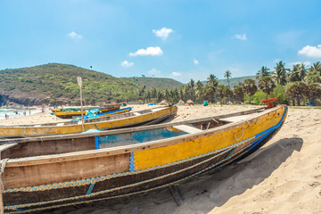 Wide view of group of fishing boats parked alone in seashore with people in the background, Visakhapatnam, Andhra Pradesh, March 05 2017
