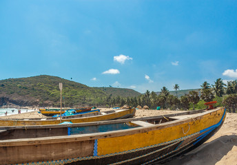 Fototapeta na wymiar Wide view of group of fishing boats parked in seashore with trees and mountain in the background, Visakhapatnam, Andhra Pradesh, March 05 2017