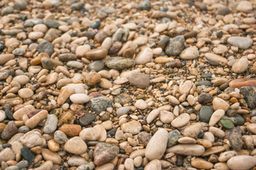 Texture of dry round colored sea pebbles on pebble beach, close-up. Pebbles stone background.  Small stones gravel texture, background from colored round stone. 