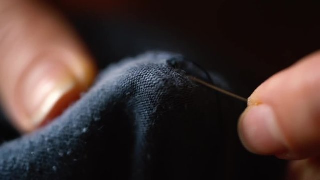 Hands of a young seamstress sewing a cloth. The dressmaker uses needle and thread to sew traditional concept