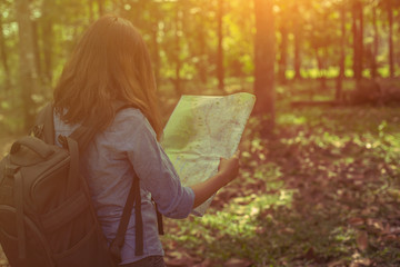 Obraz premium stylish hipster traveler exploring map at sunny forest and lake in the mountains