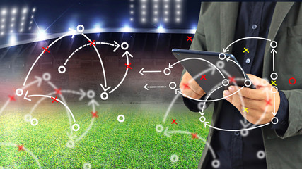Football manager planning tactic with soccer field and bright spotlights.