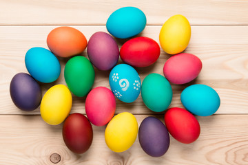 bunch of beautiful colored eggs on a wooden table top view