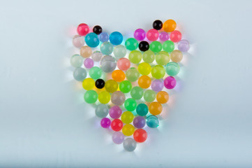 Heart made of hydrogel balls laying on white background