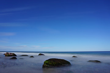 Fototapeta na wymiar Langzeitbelichtung Steine im Meer mit blauem Himmel, Ostsee, Warnemünde, Mecklenburg Vorpommern