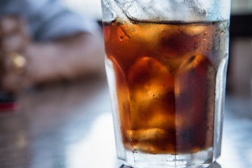 Iced cola with water drops condensed on glass surface.