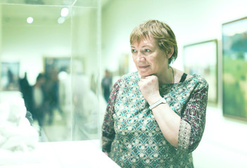 Portrait of retiree woman attentively looking at sculptures