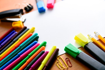 Paper, Colored pencils, pens, markers and some art stuff on wooden table.