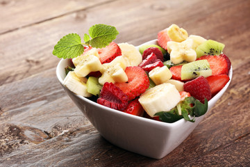 Bowl of healthy fresh fruit salad on wooden background