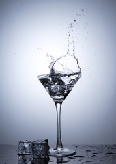 Splash from ice cube in martini glass isolated