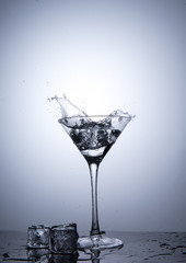 Splash from ice cube in martini glass isolated