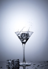 Splash from ice cube in martini glass isolated