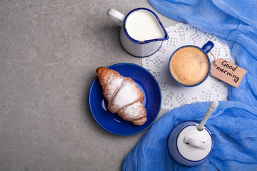 Breakfast with coffee cup, croissant and note good morning. Top view. Copy space