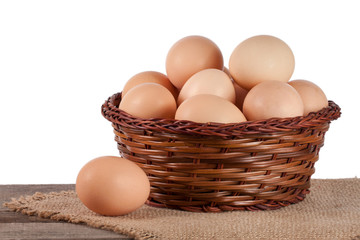 eggs on a wooden table in a wicker basket on a white background