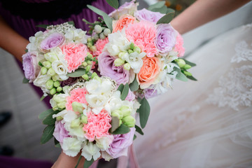 Bride and bridesmaids hold in their hands pink wedding bouquets made of roses and peonies