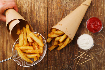 Preparation portion of Belgian fries in a paper tube, with or without a dip. On a wooden table.