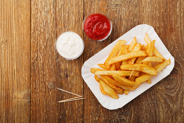 Serving Belgian fries served on a paper tray, with or without a dip. On a wooden table.
