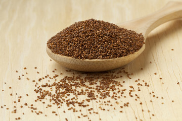Brown teff seeds on a wooden spoon