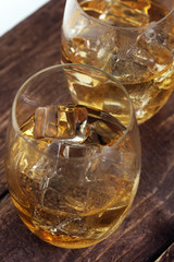 glass of whiskey with ice on a wooden