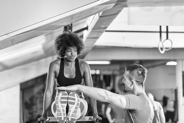 Fototapeta na wymiar black woman doing parallel bars Exercise with trainer