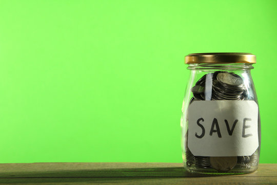 Coins in a jar on a green background. The concept of savings
