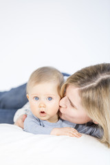 beautiful mother and baby boy lying in bed in child room