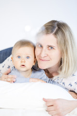 beautiful mother and baby boy lying in bed in child room