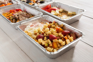 Healthy food take away in foil boxes on wood background