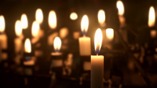 Video footage of Easter candles glowing in the church with one of the candle blown at night
