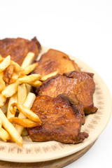 Baked pork chops with french fries served on the plate
