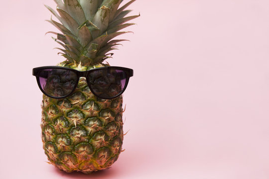 pineapple on a pink background with sunglasses