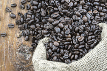 closeup of coffee beans spill on wood.