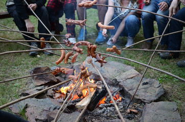 Sausages barbecue on the stick above the fire in the nature
