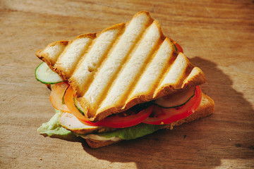 Closeup of ham and vegetables - tomatoes, cucumbers - on whole wheat bread.