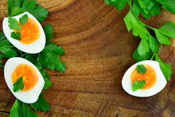 Hartgekochte halbierte Eier mit Petersilie am Holztisch mit Textfreifeld