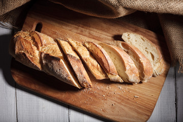Sliced baguette on wood board.