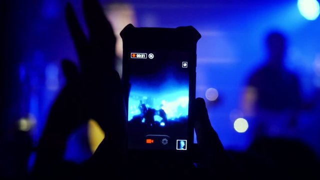 Fans waving their hands recording video and taking pictures with smart phones at music concert. 3840x2160