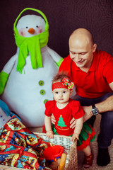 Father holds funny little girl while she stands before large basket