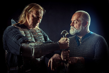 Two powerful knights are holding one sword.